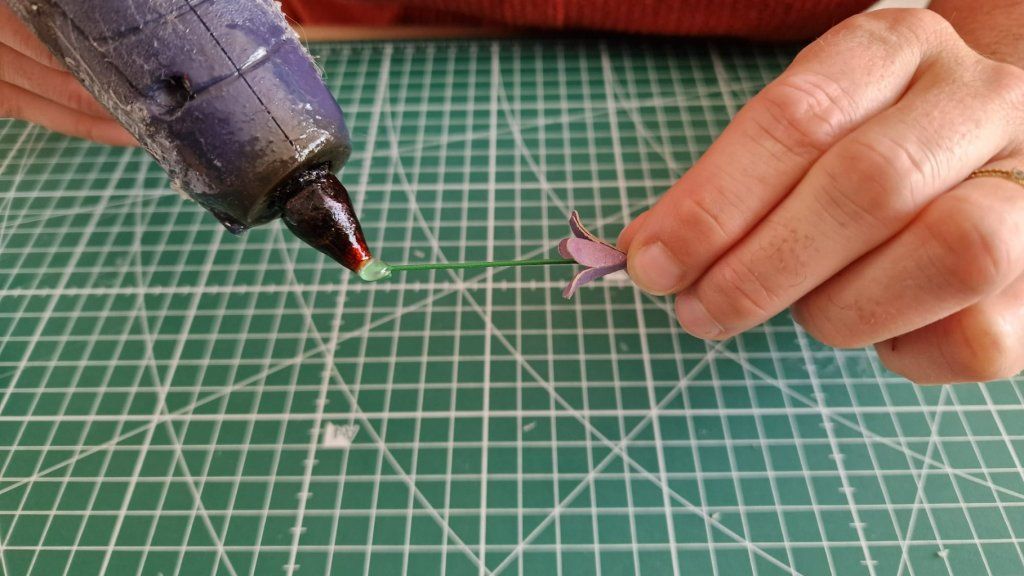 3)Faire une toute petite boucle, à l'extrémité de la tige.
4)Appliquer de la colle chaude sur cette boucle et y fixer la première fleur. Enfiler la tige dans la fleur.