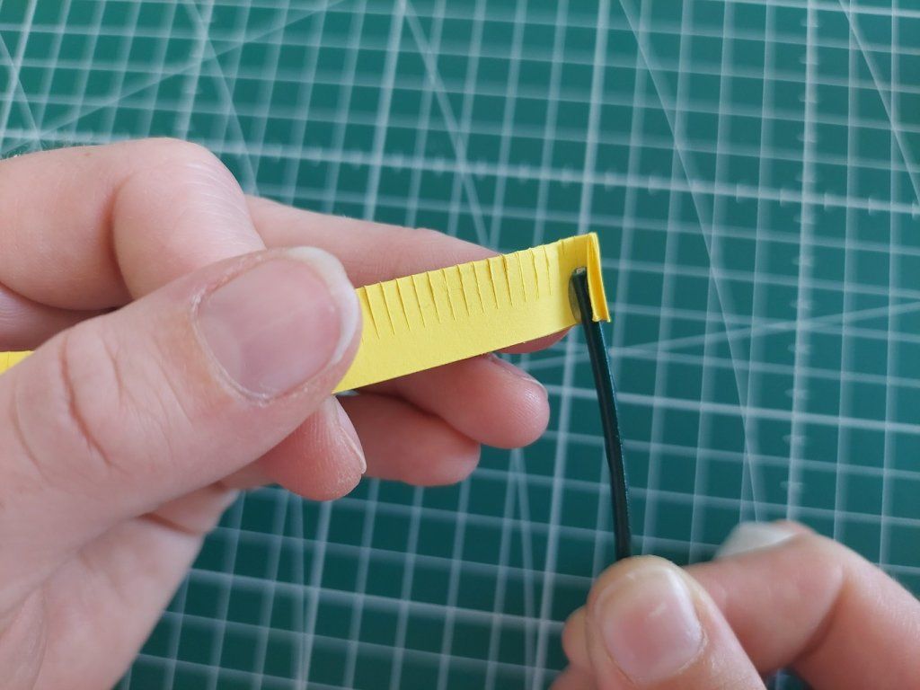 2° : Coller perpendiculairement, à la colle chaude, l'extrémité de la tige au bout de la bande jaune.