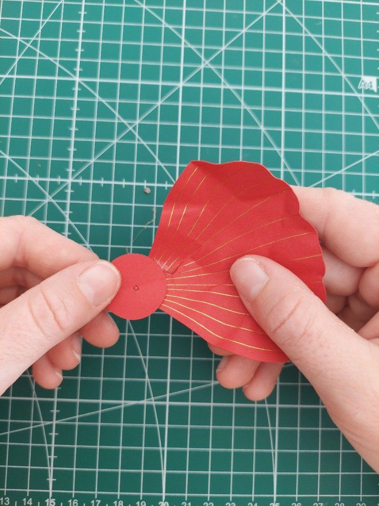 9)- Coller, à la colle chaude, les grandes pétales sous le cercle de papier rouge.